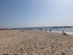 um grupo de pessoas numa praia perto do oceano em Carminho beach house em Vila do Conde