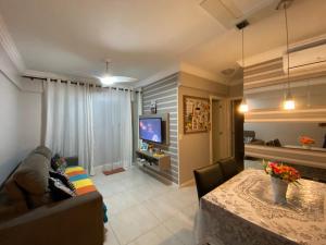 sala de estar con sofá, mesa y TV en Apartamento Centro Bombinhas, en Bombinhas