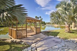 a wooden gazebo next to a river with palm trees at Waterfront Harlingen Home with Pool, Patio and Gazebo! in Harlingen