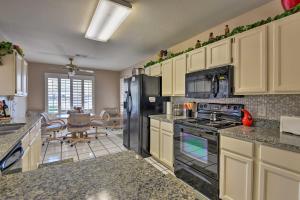 a kitchen with black appliances and a dining room at Mesa Home with Pool about 7 Mi to Riparian Preserve! in Mesa