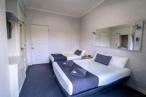 a hotel room with two beds and a mirror at Kingsford Riverside Inn in Brisbane