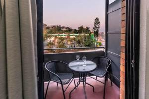 una mesa y sillas en un balcón con vistas en Kingsford Riverside Inn, en Brisbane