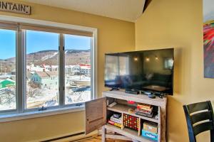 a living room with a flat screen tv next to a window at Lincoln Condo with Mtn Views, 2 Miles to Ski Resort! in Lincoln