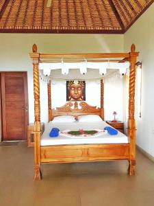 a bedroom with a wooden bed with a statue on it at Jemeluk Beach Bungalows in Amed