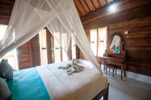 une chambre avec un lit à baldaquin et un bureau dans l'établissement Timbool Bungalow, à Nusa Penida