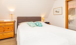 1 dormitorio con cama blanca y tocador de madera en Haus Jungnamen Sand Whg. 14 en Wittdün