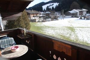een balkon met een tafel en uitzicht op een met sneeuw bedekt veld bij Zagglhaus in Scheffau am Wilden Kaiser