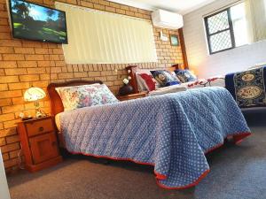a bedroom with a bed and a tv on a brick wall at Gowrie Agapanthus in Singleton