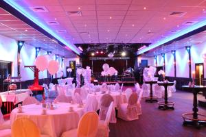 un salón de banquetes con mesas y sillas blancas y globos rosados en Hotel Parkzicht en Veendam