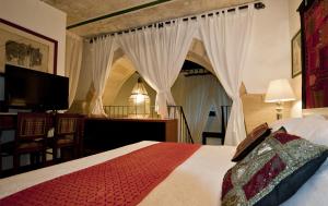 1 dormitorio con 1 cama con cortinas y TV en Dei Due Portoni Suite Storica, en Lecce