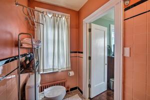 a bathroom with orange walls and a toilet and a window at Walk to Shops, Dining & City Park: Reading Apt in Reading +20 photos
