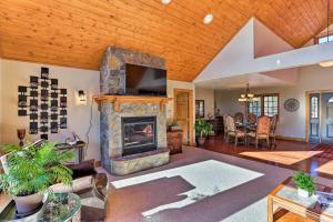 a living room with a stone fireplace and a tv at Cabin with Deck and Fire Pit, 9 Mi to Mt Rushmore! in Keystone