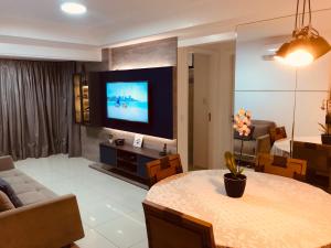 a living room with a table and a tv in it at Apartamento Beira Mar Maceió in Maceió