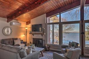 een woonkamer met een open haard en grote ramen bij Renovated and Cozy Cottage on Cayuga Lake Wine Trail in Seneca Falls