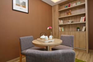 Atour Hotel (Xi'an Gaoxin Dazhai Road) في شيان: غرفة معيشة مع كرسيين وطاولة ورف كتاب