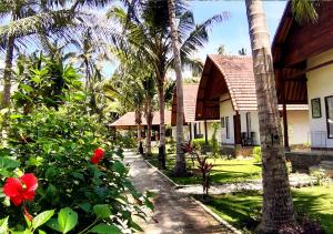 ein Haus mit Palmen und einem Garten mit roten Blumen in der Unterkunft Crystal Bay Villa & Residence in Nusa Penida