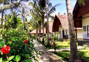 una casa con palme e un giardino con fiori rossi di Crystal Bay Villa & Residence a Nusa Penida