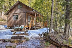 una cabaña en el bosque con una mesa de picnic y nieve en Private Yaak River Hideaway with Deck and Mtn Views! en Troy