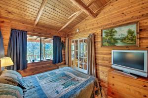 1 dormitorio con 1 cama y TV de pantalla plana en Private Yaak River Hideaway with Deck and Mtn Views! en Troy
