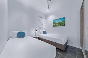 Un dormitorio blanco con dos camas y una ventana. en Modern Beach Front Apartment, en Airlie Beach 14 fotos más