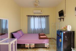 Mały pokój z fioletowym łóżkiem i lodówką. w obiekcie Thippawan Bungalow w mieście Ko Si Chang
