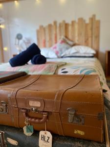 una maleta marrón sentada encima de una cama en Alpacas Off Grid - Eco Cabin en Takaka
