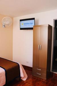 a bedroom with a bed and a tv on the wall at Aristides Inn in Huarmey