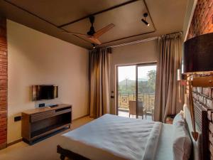 Habitación de hotel con cama y balcón en Advait Resort Kshetra Mahabaleshwar, en Mahabaleshwar