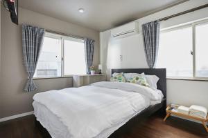 1 Schlafzimmer mit einem großen weißen Bett und 2 Fenstern in der Unterkunft Ka's house in Tokio