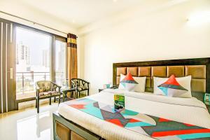 a bedroom with a large bed and a large window at FabExpress Hemkunt Residency Noida in Noida