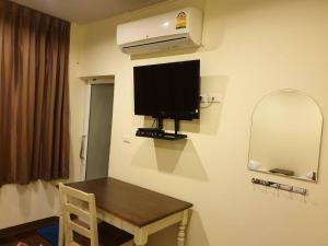 a room with a table and a television on the wall at Papermoon Guesthouse in Bangkok
