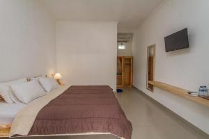 um quarto com uma cama grande e uma TV de tela plana em Ratna Guest House em Ubud mais 8 fotografias