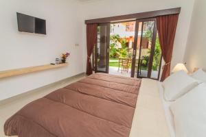 a bedroom with a large bed and a balcony at Ratna Guest House in Ubud