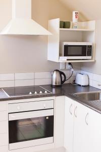 a kitchen with white cabinets and a microwave at Spacious, Peaceful, Fully Equipped 1BR Apartment in Upper Hutt