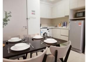 una cocina con una mesa negra con platos y sillas blancos en I City Residence, 2 Bedroom 4-7 Pax unit, Walking to Theme n Water Park & Shopping Mall, en Shah Alam