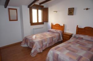 Un dormitorio con dos camas y una ventana. en Casa Rural Os Arregueses, en Alquézar
