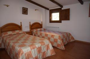 a hotel room with two beds and a window at Casa Rural Os Arregueses in Alquézar
