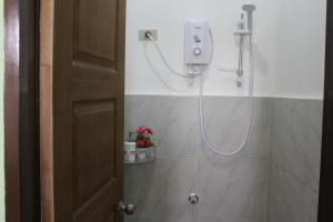 a shower in a bathroom with a hose on the wall at FilCan Hostel/Backpackers in Coron