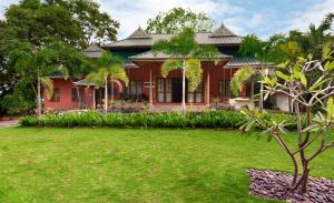 a red house with a lawn in front of it at Eco Garden Resort & Heritage Cheruthuruthy Thrissur in Cheruthuruthi