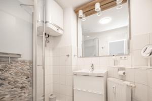 a white bathroom with a sink and a mirror at Haus Dünenbake, Ferienwohnung Strandpeter Meerblick (Wohnung 47) in Sankt Peter-Ording +17 photos