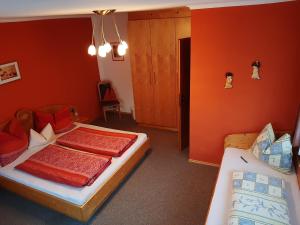 2 camas en una habitación con paredes de color naranja en Hutmannhof-Ferienwohnungen, en Dellach