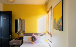 a bedroom with a bed and a yellow wall at Flora Hotel Hue in Hue