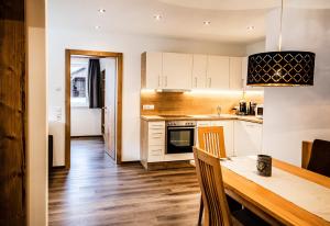 a kitchen with white cabinets and a wooden table at Allmi Appartement in Sankt Gallenkirch