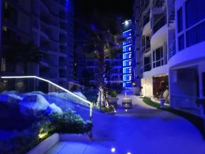 a city street at night with a palm tree and buildings at Grand Avenue Residence 1 bedroom in Pattaya Central