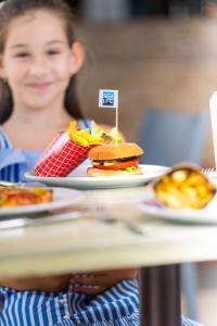 a woman sitting at a table with a sandwich and french fries at Sealife Family Resort Hotel in Antalya