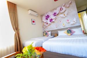 two beds in a room with flowers on the wall at Flora Hotel Hue in Hue