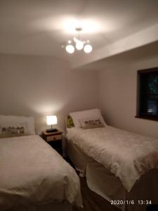 1 dormitorio con 2 camas y una lámpara en una mesa en Glen Lodges en New Milton