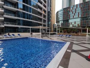 a large swimming pool with chairs and buildings at Icon Casa Living - Bay Central Tower Marina View I in Dubai