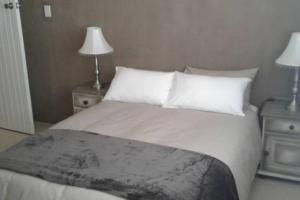 a bedroom with a white bed with two night stands at Angel's Place by the Sea in Hermanus