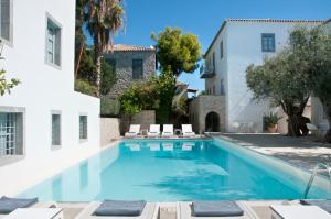 a swimming pool in front of a white building at Orloff Resort in Spetses